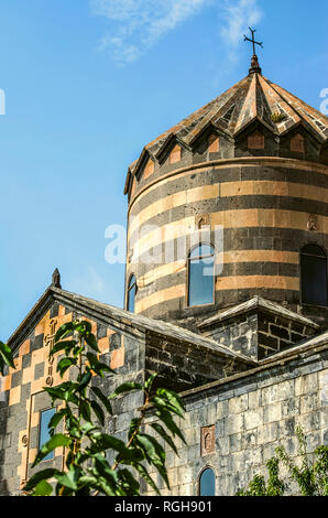Facade wall with a relief cross under the roof and an umbrella dome with an iron cross in the monastery of St. George, Mughni village in Armenia Stock Photo