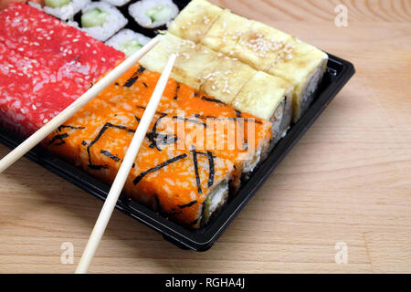 Sushi pieces on square tray on brown wooden table side view closeup Stock Photo