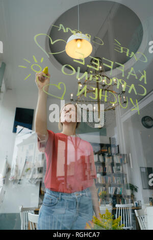 Young woman writing offer on windowpane in a cafe Stock Photo