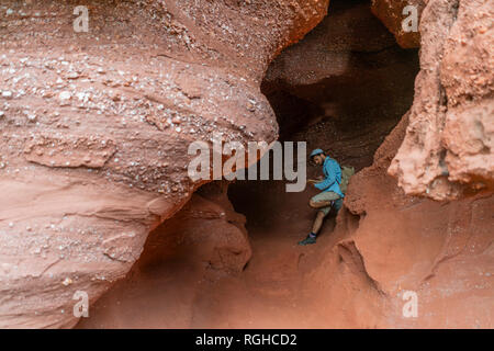Young man sitting in a cave, looking at map Stock Photo