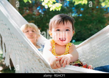 Spain, Grandma and baby relaxing in a hammock in the garden in the summer Stock Photo