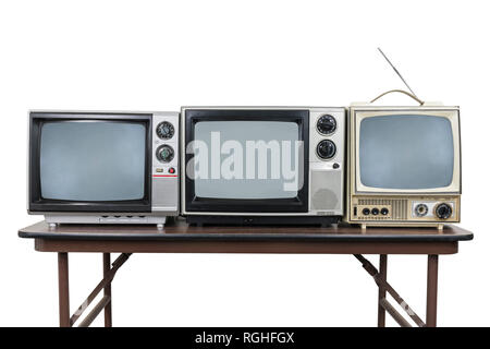 Three vintage televisions on wood table isolated on white with clipping path. Stock Photo