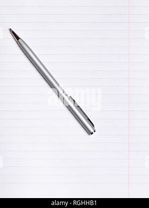 On a sheet of paper notebook with lines lies a silver pen. Copy space. Education concept Stock Photo