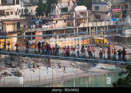 People walking across Ram Jhula suspension bridge over the Ganges river in Rishikesh, Uttarakhand, India Stock Photo