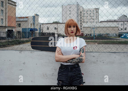 Cool young woman with carver skateboard standing outdoors Stock Photo