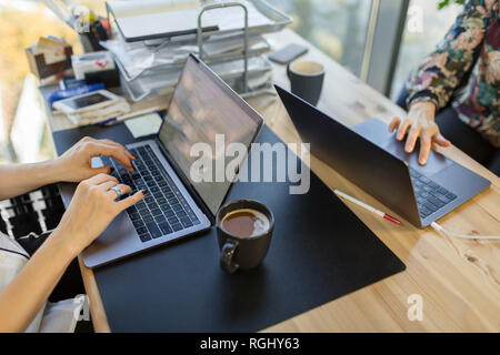 Close-up of two women using laptops at desk in office Stock Photo