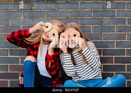 Two girls having fun with doughnuts Stock Photo