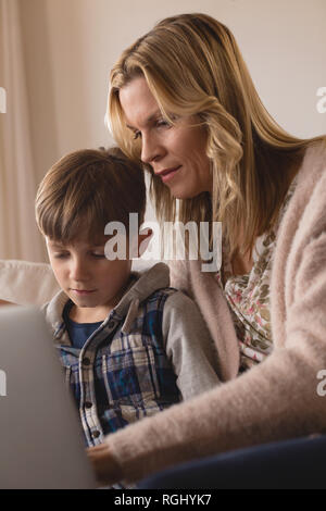 Front view of concentrated mother helping her son use laptop in living room at home Stock Photo