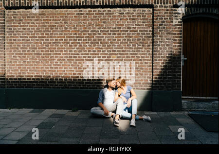 Netherlands, Maastricht, young couple having a break in the city sitting on sidewalk Stock Photo