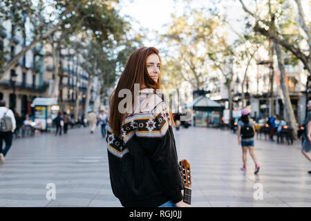 Red-haired woman with a guitar in the city