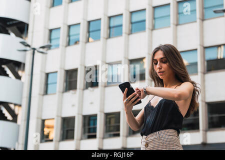 Portrait of young woman with cell phone checking the time Stock Photo