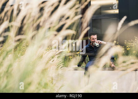 Businessman sitting outside, taking a break, drinking coffee Stock Photo