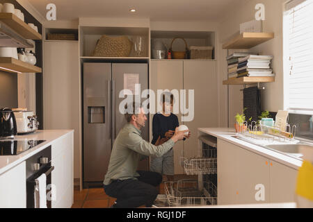 Father and son arranging dirty dishes in dishwasher Stock Photo