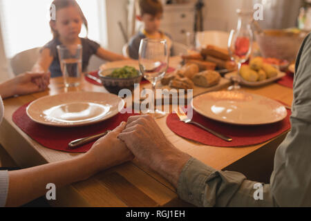 Close up of family praying before having food on dining table at home Stock Photo
