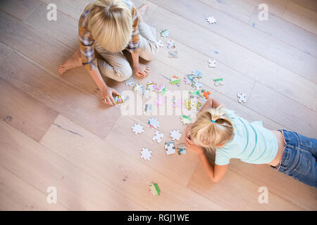 Brother and sister lying on the floor at home playing jigsaw puzzle Stock Photo