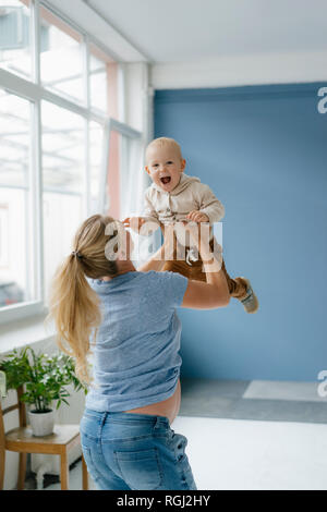 Pegnant mother lifting up happy toddler son Stock Photo