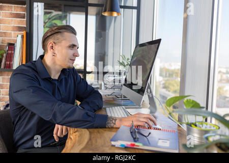 Smiling man working on computer at desk in office Stock Photo