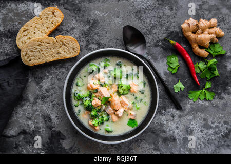 Cocos salmon soup, with broccoli, leek, coconut milk, parsley, chili pod, ginger and baguette Stock Photo