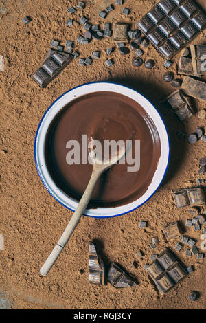 Melted Chocolate in a bowl surrounded by chocolate pieces and cocoa powder Stock Photo
