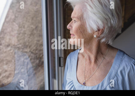 Senior woman looking through window Stock Photo