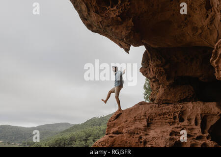 Young man balancing on the edge of an abyss Stock Photo