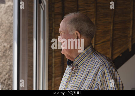 Senior man looking through window Stock Photo