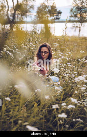 Young woman crouching in flower meadow Stock Photo