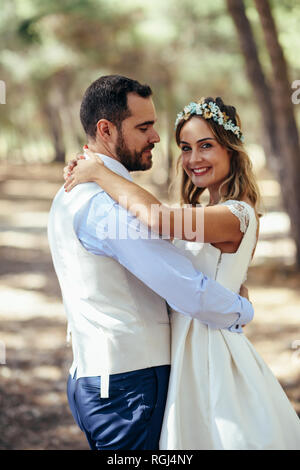 Portrait of happy bride dancing with her groom in pine forest Stock Photo