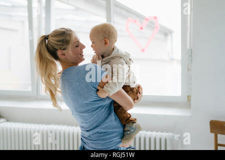 Happy pregnant mother carrying toddler son Stock Photo
