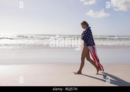 Young woman wrapped in American flag at beach Stock Photo