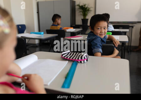 Happy schoolboy looking back in classroom Stock Photo