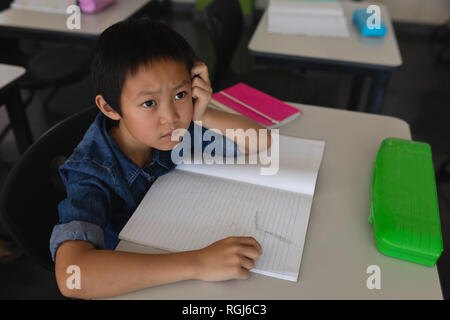 Schoolboy looking away in classroom Stock Photo