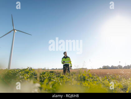 Engineer standing in a field at a wind farm Stock Photo