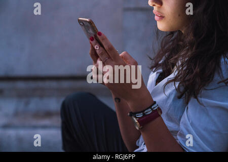 Young woman using cell phone at twilight, partial view Stock Photo