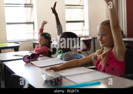 Schoolgirls raising hand in classroom of elementary school Stock Photo