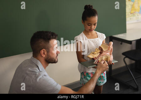 Male teacher explaining anatomical model to schoolgirl in classroom Stock Photo