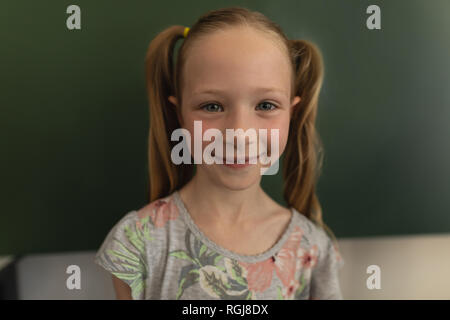 Close-up of happy schoolgirl looking at camera in classroom Stock Photo