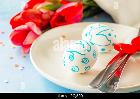 Easter table setting with tulips flowers and cutlery on stone table. Holidays background. Stock Photo