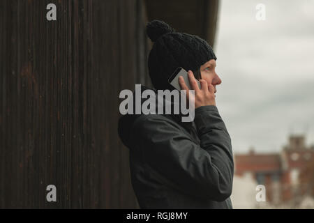 Worried woman talking on mobile phone on street on cold winter day Stock Photo