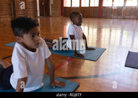 Schoolkids doing yoga on a yoga mat in school Stock Photo