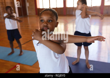 Schoolgirl doing yoga on a yoga mat in school Stock Photo