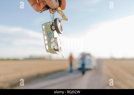 Hand holding camper van key in rural landscape Stock Photo