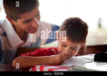 Father helping his son with his homework on a table. Stock Photo