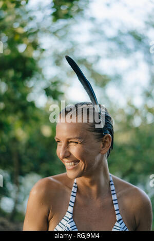 Portrait of happy woman with wet hair wearing feather in her hair Stock Photo