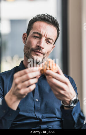 Mature man sitting in office assembling wooden cube puzzle Stock Photo