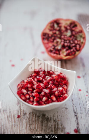 Bowl of pomegranate seed and half of pomegranate in the background Stock Photo