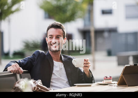 Businessman sitting in cafe, drinking coffee, using smartphone Stock Photo