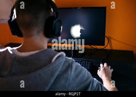 Young man sitting at his PC, playing computer games Stock Photo