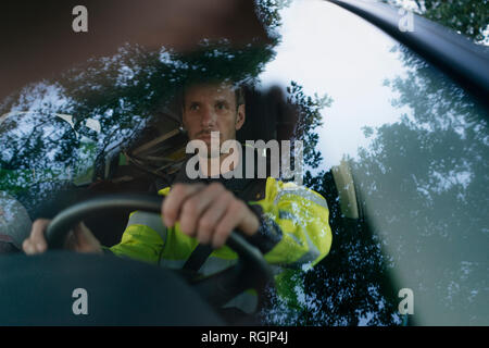 Man in protective workwear driving car Stock Photo