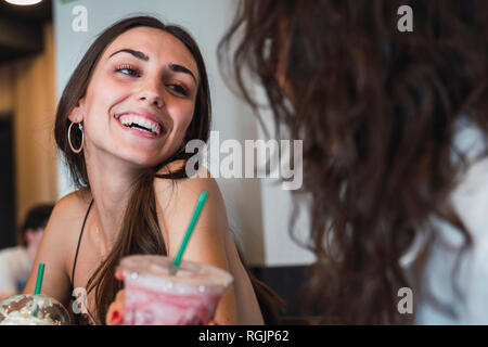 Portrait of happy young woman in a coffee shop having fun with her friend Stock Photo